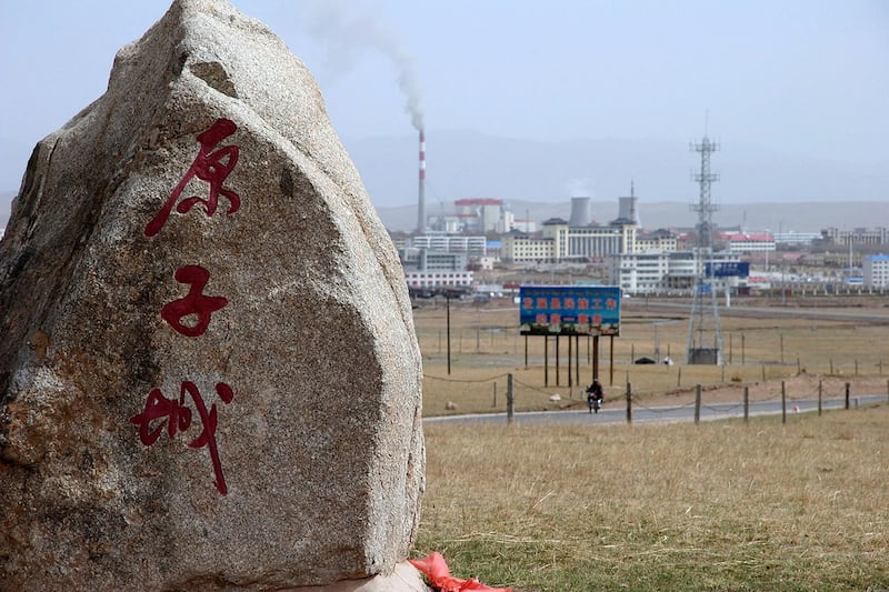 2007 年 5 月 12 日，中国青海省海盐市，在通往中国第一个核武器基地的道路上，一块纪念碑石标志着“核城”，背景是一座新的工业城市，该基地已解密并向游客开放。（法新社）