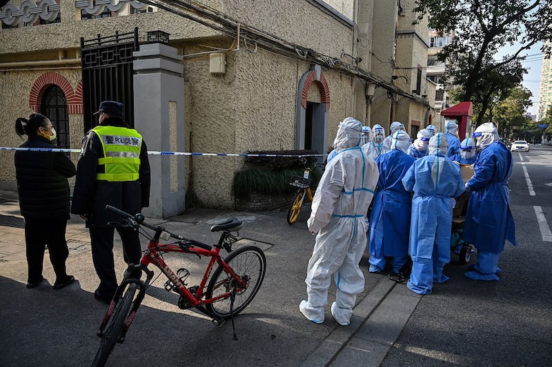 2022 年 3 月 23 日，穿着防护装备的卫生工作者在上海一住宅区。（法新社 ）