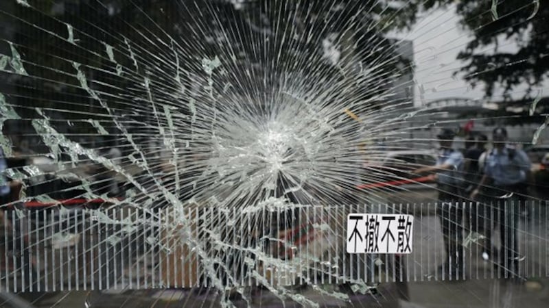 警方在香港立法会大楼破损的一面玻璃窗外执勤(美联社)